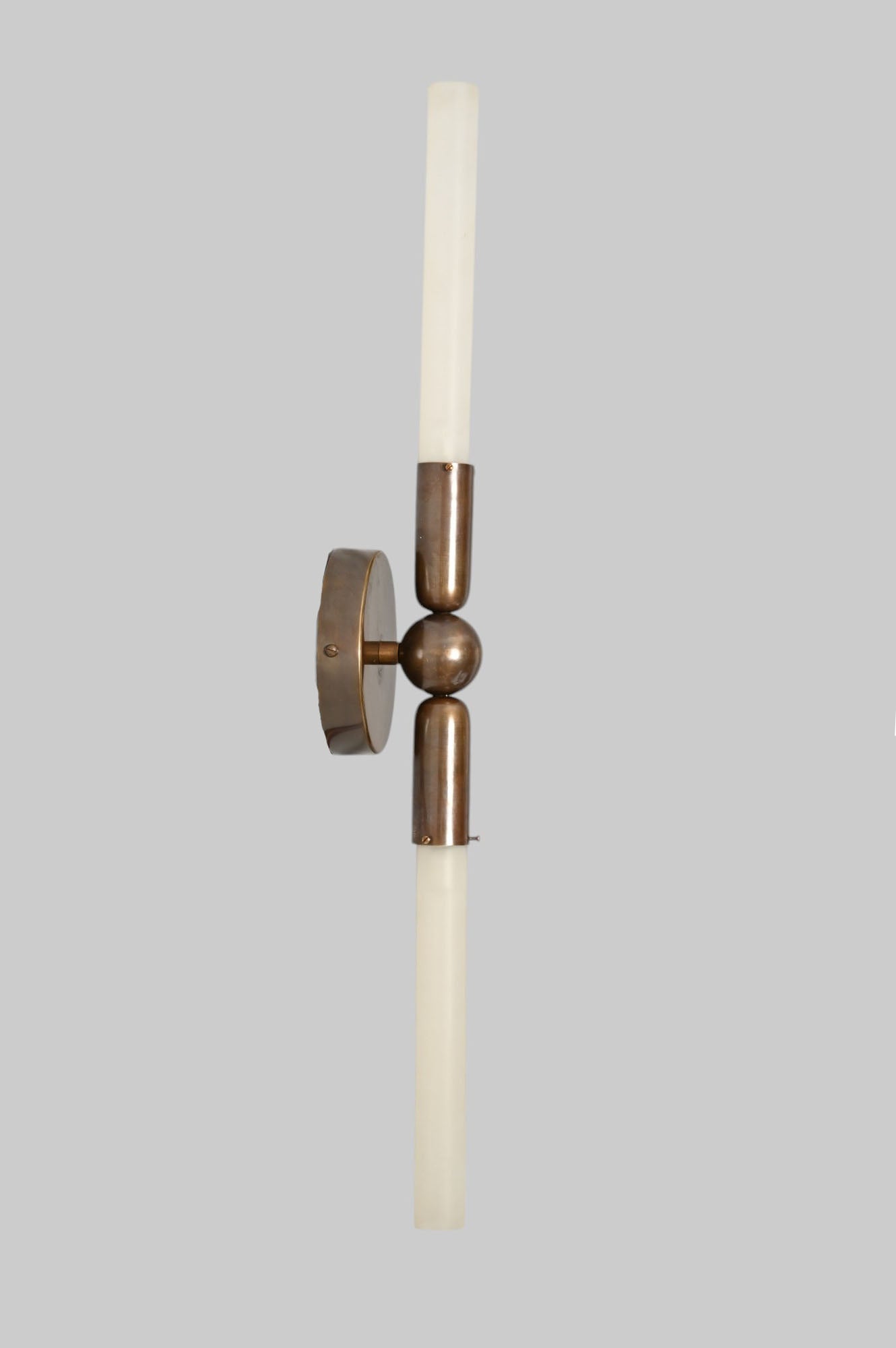 Glass Tube Wall Sconce in Raw Brass blends modern style with industrial charm